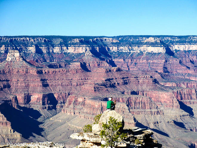 The climbers on the rock outcropping help to demonstrate the immense scale of the Grand Canyon.