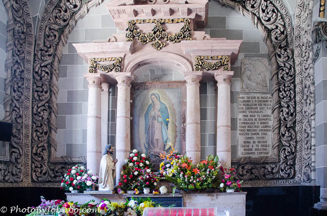 At the rear of the church a small altar is adorned with fresh flowers.