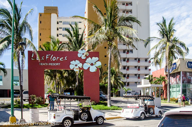 Two pulmonia taxis await passengers in front of a resort.